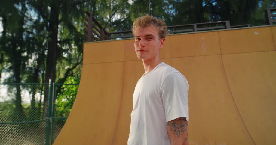 The teenager is standing on the ramp with his skateboard