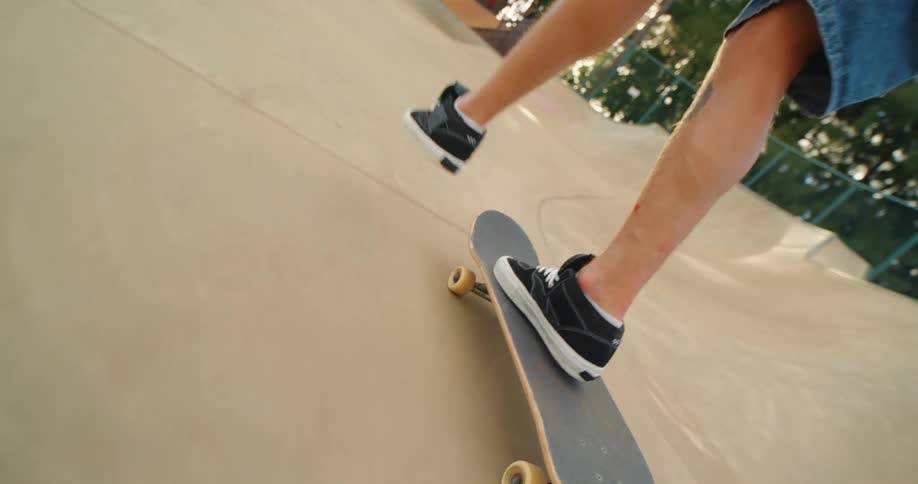 A person is captured in a dynamic closeup shot their feet expertly maneuvering a skateboard on a concrete ramp at a skate park