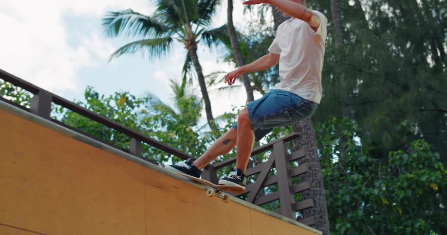 A young man riding a skateboard on a ramp in a public park at midday