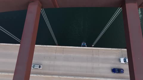 Aerial view of a river under a bridge with vehicles crossing