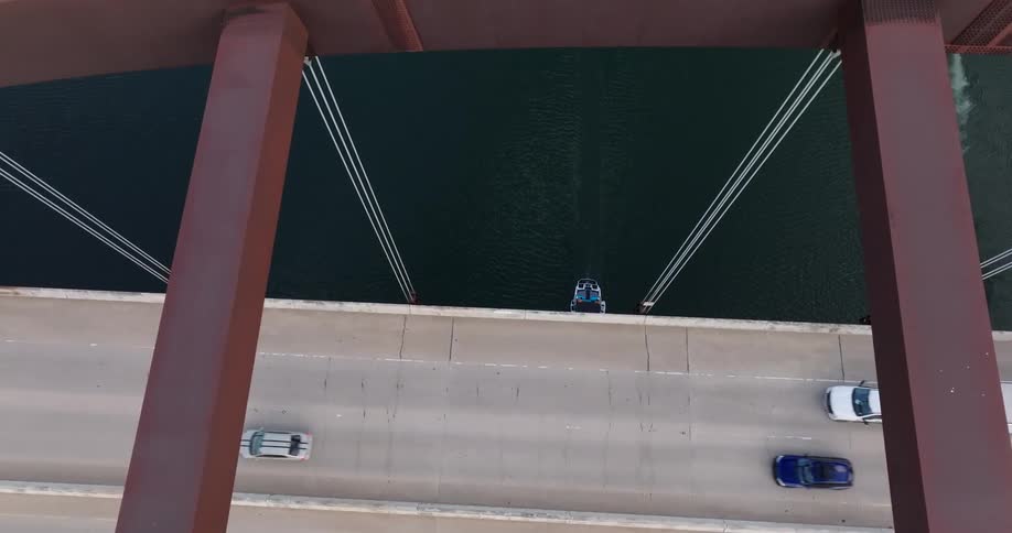 Aerial view of a river under a bridge with vehicles crossing