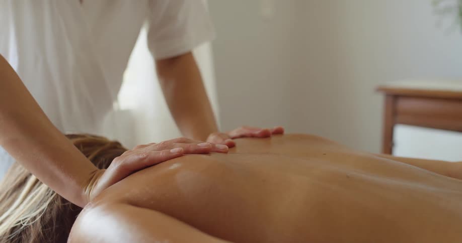 A woman receiving a massage from another woman in a spa at midday