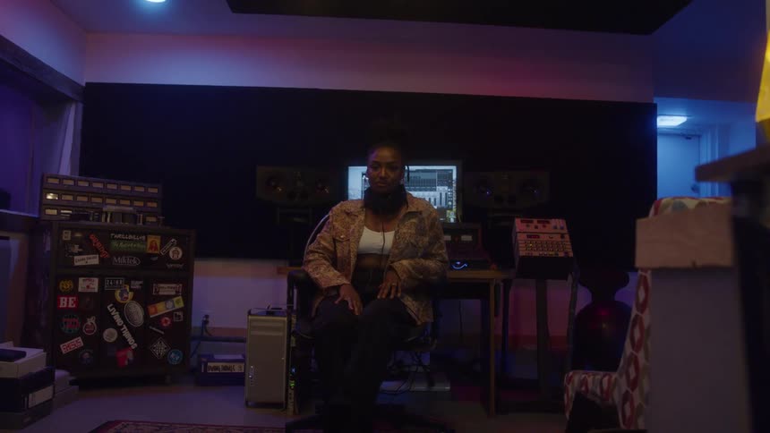 Woman sitting in a recording studio lit by colorful lights