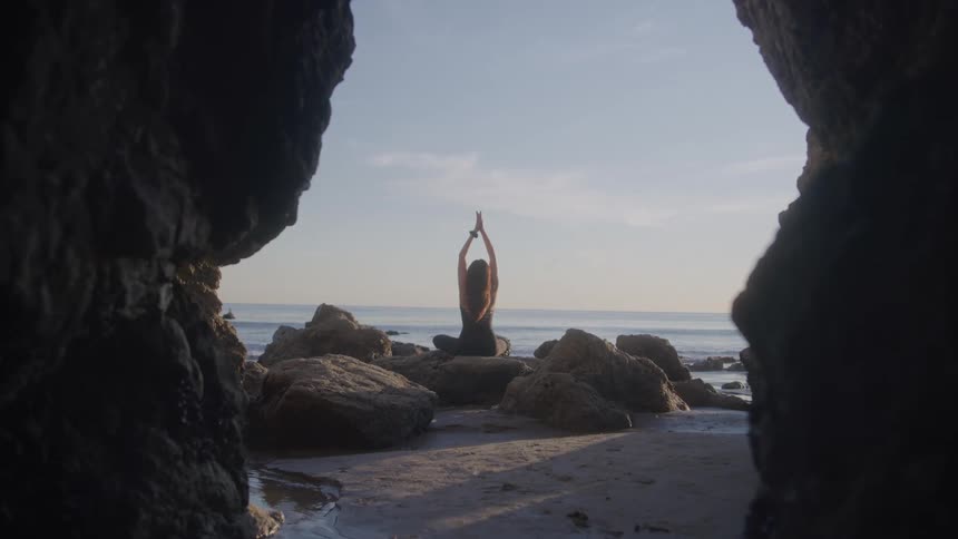 The woman is doing yoga outside the cave