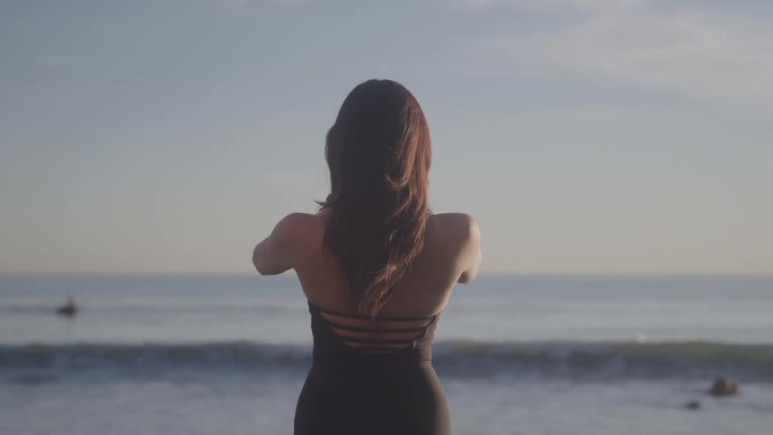 Woman meditates on coastal rocks at sunrise