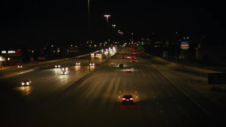 Cars drive on a lit highway at night