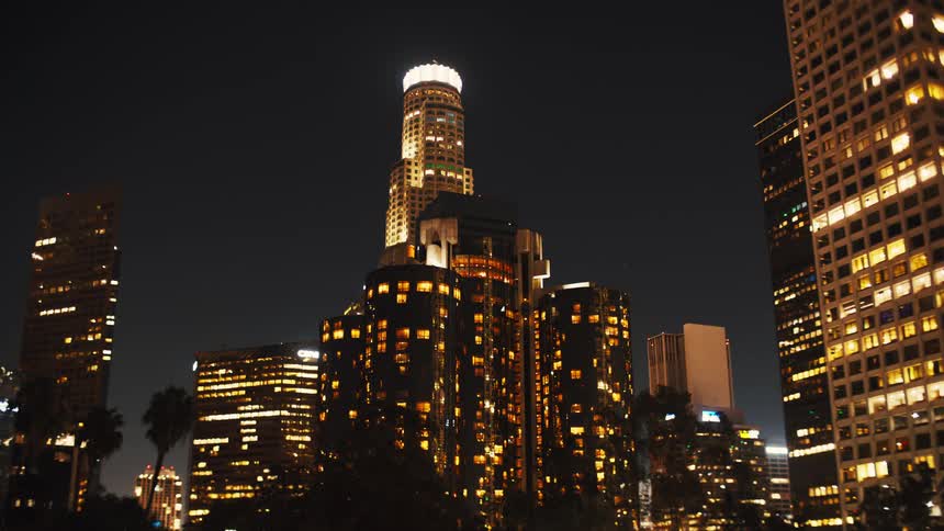 The city at night with a series of highrise buildings and skyscrapers their lights illuminating the surroundings