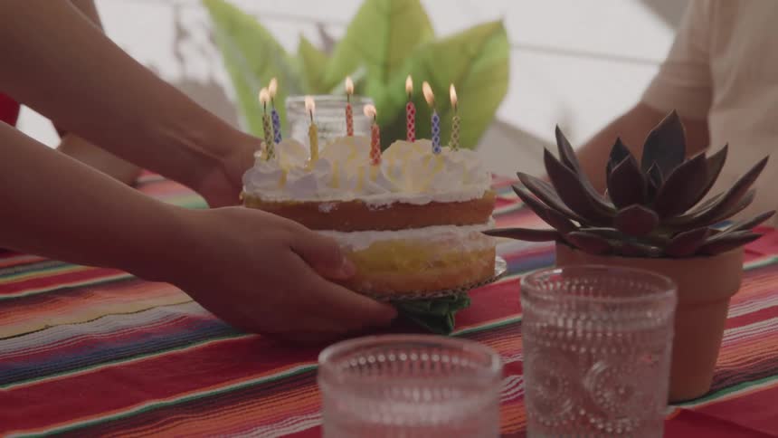 Cake with lit candles is placed on the colorful table