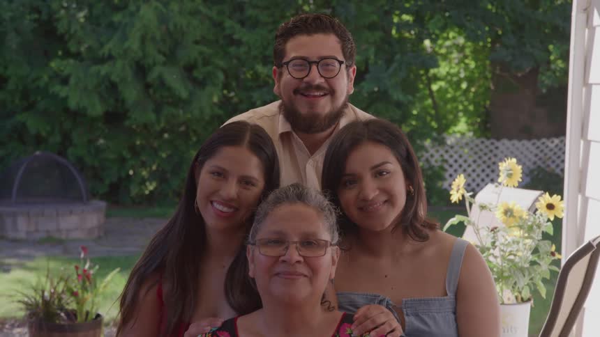 Smiling family poses outdoors on a sunny day
