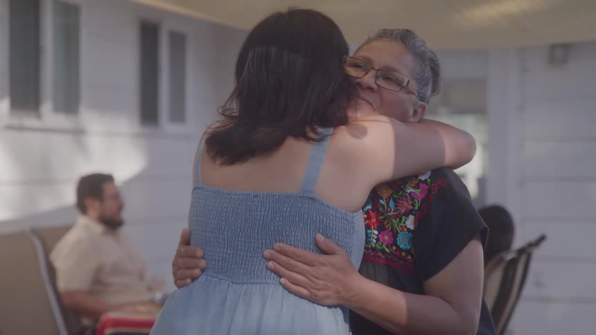 Two women hug and walk over to the table