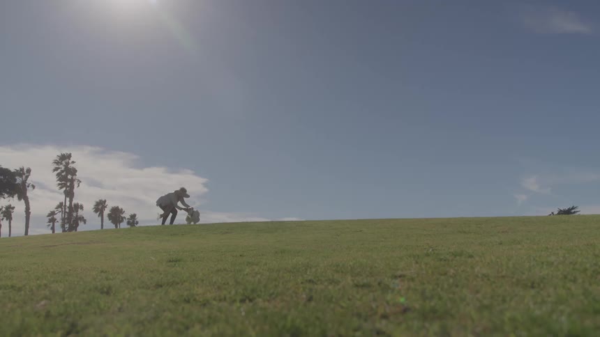 A woman plays fetch with a dog on a grassy field