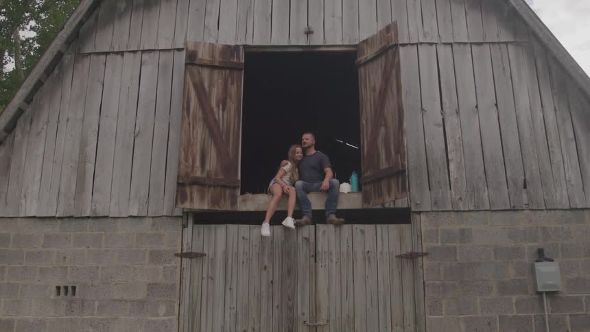 A father hugs his daughter in the barn