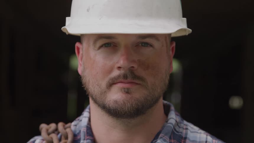 Man wearing safety helmet looks intently with a serious expression