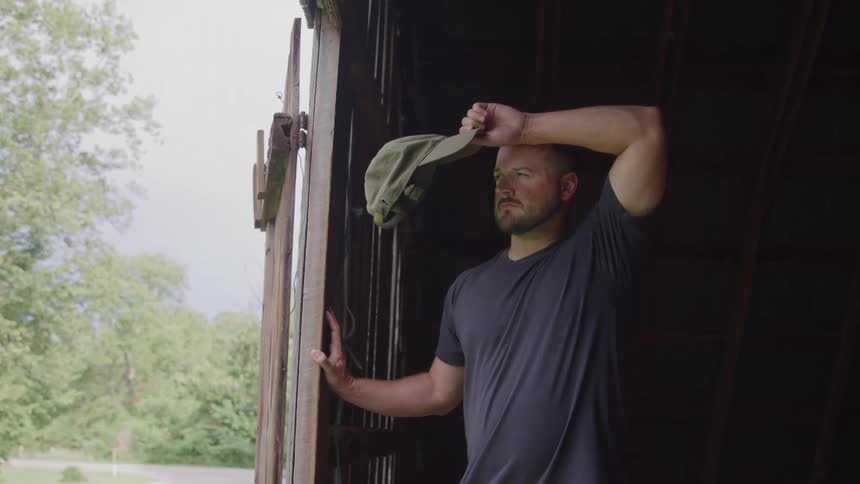 The man wipes his brow in the barn