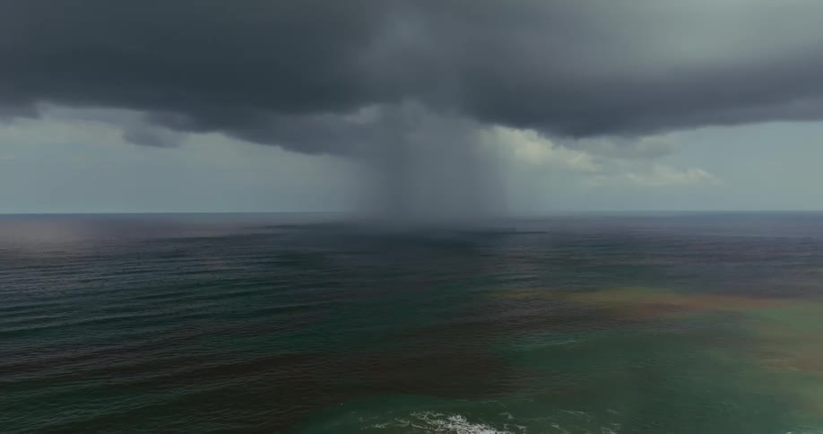 The ocean under dark clouds covering the sky signaling an approaching storm at midday