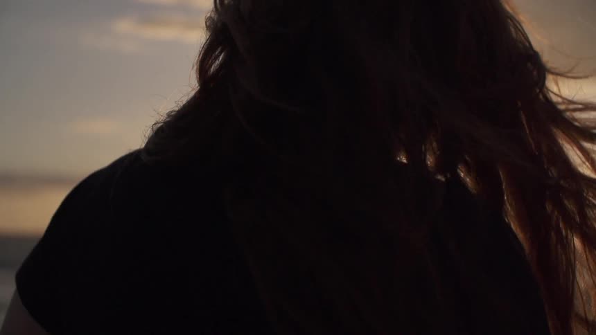 A woman's hair blows around near a beach