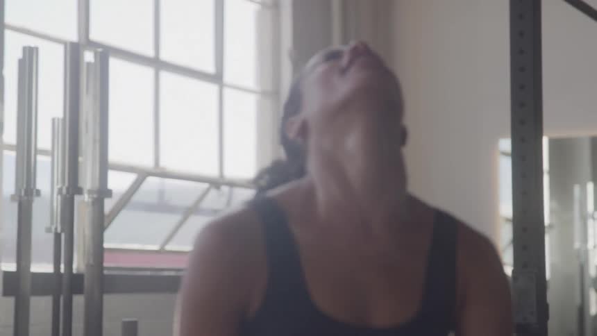 A woman finishes exercising and then smiles while flexing her arms triumphantly