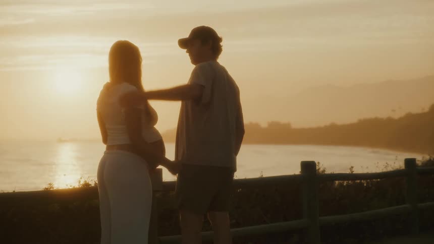 Couple embraces while watching the sunset by the sea