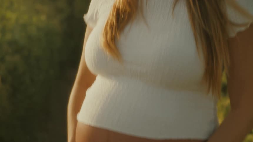 A pregnant woman places her hands on her belly while looking at the ocean