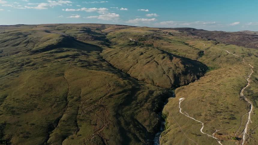 Landscape of vast hills covered with low vegetation under a blue sky
