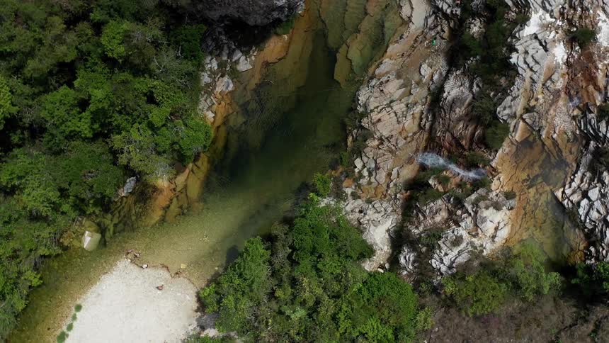 Rock formation with a small waterfall flows into a green water pool