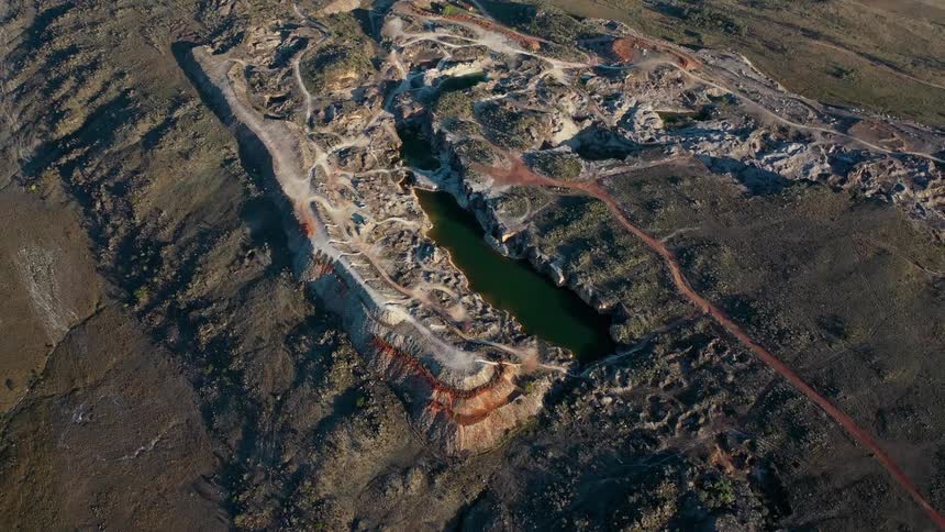 Aerial view of lake in rocky area surrounded by dirt roads