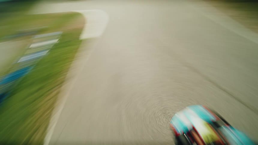 A firstperson perspective shows a gokart speeding around a curved track the camera captures the ground rushing by as the kart navigates the turn