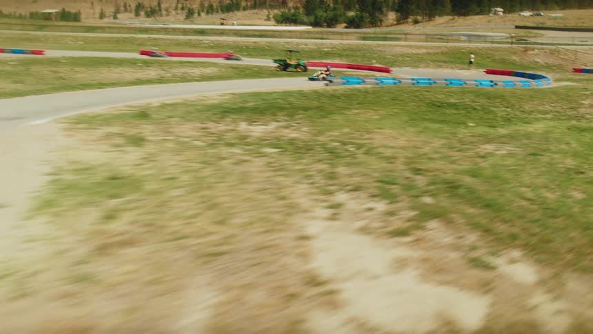 A firstperson perspective shows a gokart speeding around a curved track the camera captures the ground rushing by as the kart navigates the turn
