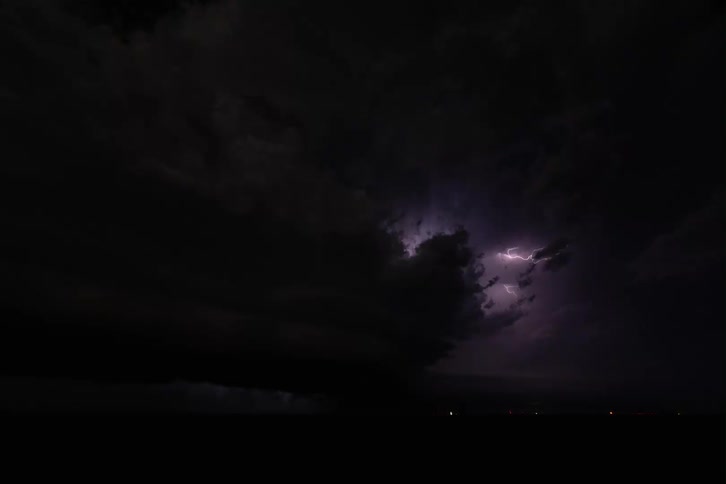 Chaotic lightning flickers through black storm clouds in a timelapse
