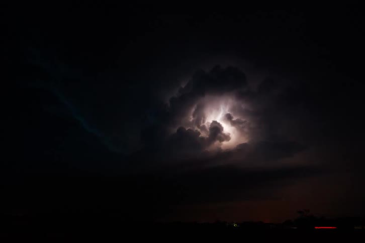 Lightning exploding inside dense storm clouds at night