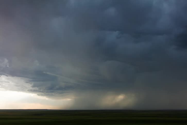 Dark storm clouds gather and start rotating over the rural countryside during the daytime
