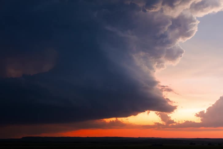 Dark storm clouds roll across the sky at sunset