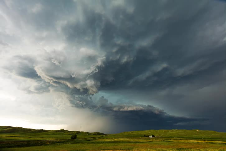 Storm clouds move over rural land as lightning flashes in the sky