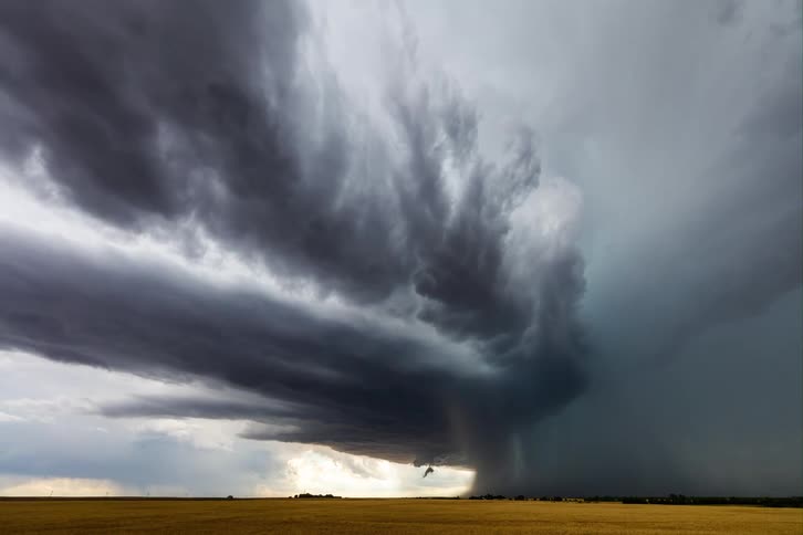 A dramatic timelapse shows a massive rotating supercell thunderstorm forming over a flat golden field