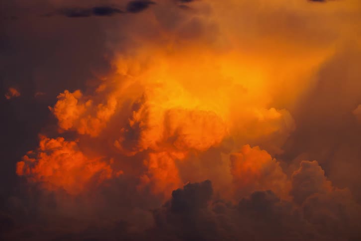 Glowing orange clouds light up the dramatic sky under warm sunlight