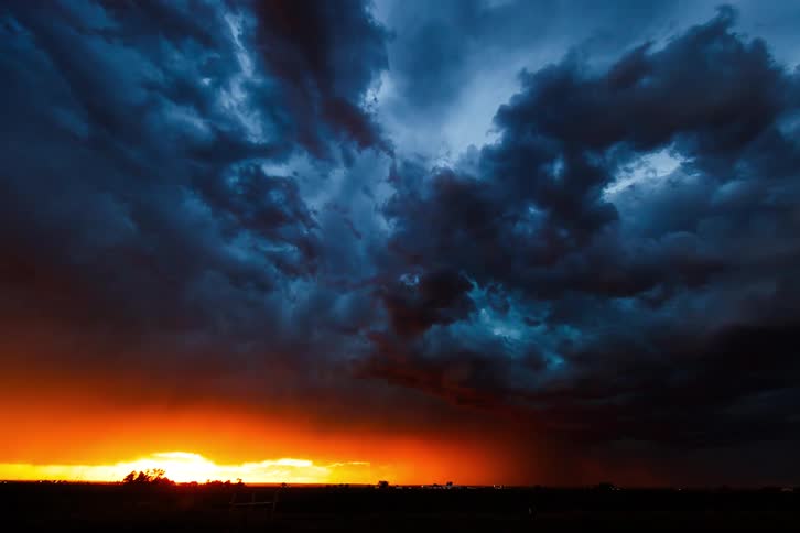 Black ominous clouds thunder storming with lighting bolts in the countryside