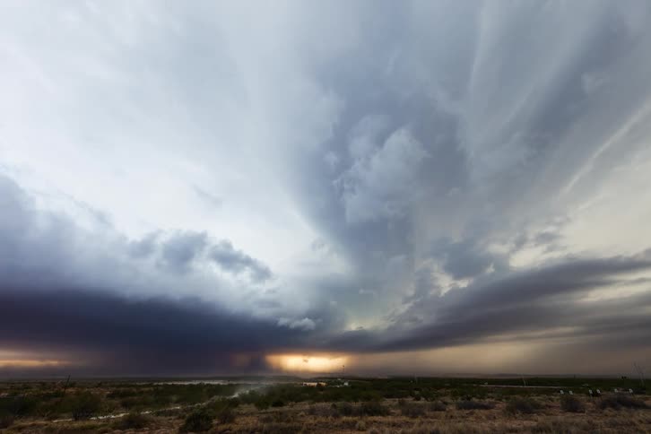 Storm clouds flow in opposite directions on top of each other over a field