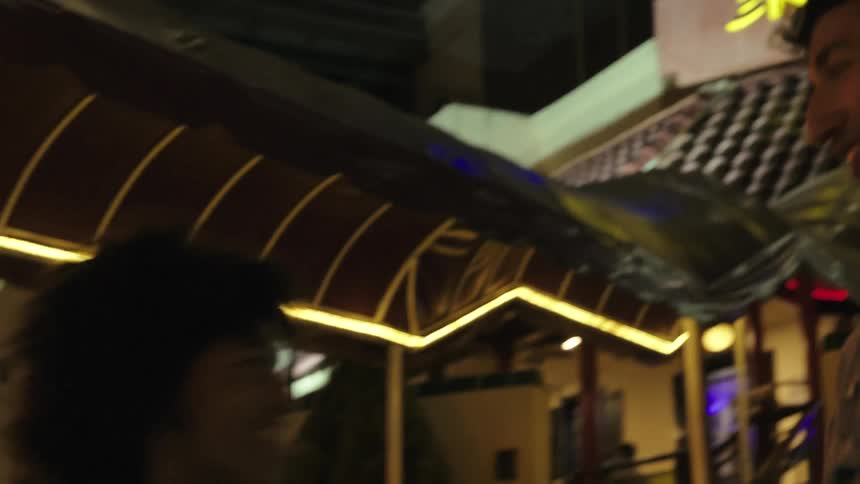 A man talks on the phone and greets his friend