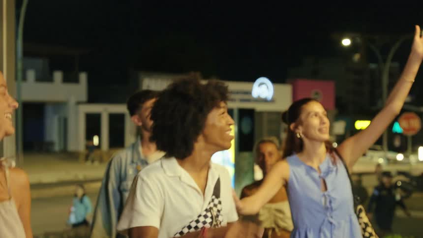 Friends smile while exploring the city at night near a busy street