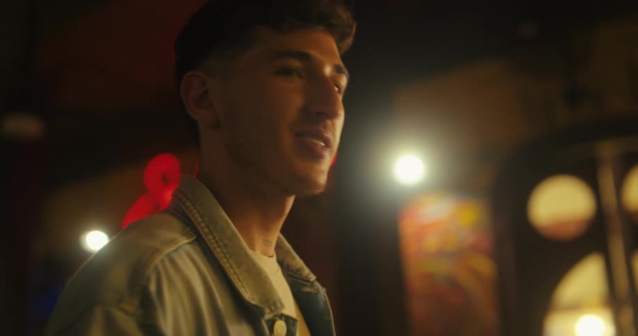 A young man smiles and gestures as hes talking with friends