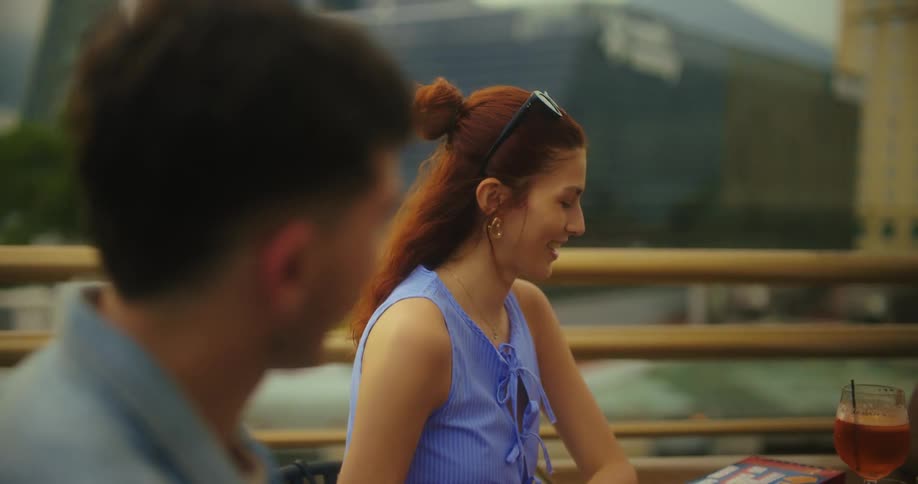 Friends sit at a table on a balcony in the city during daytime