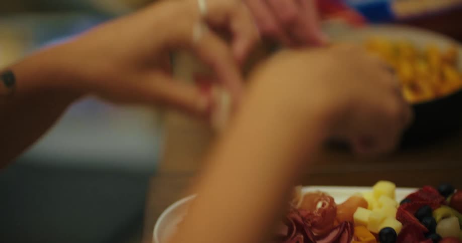 Woman serves herself from a tray of food while a friend dips their bread nearby