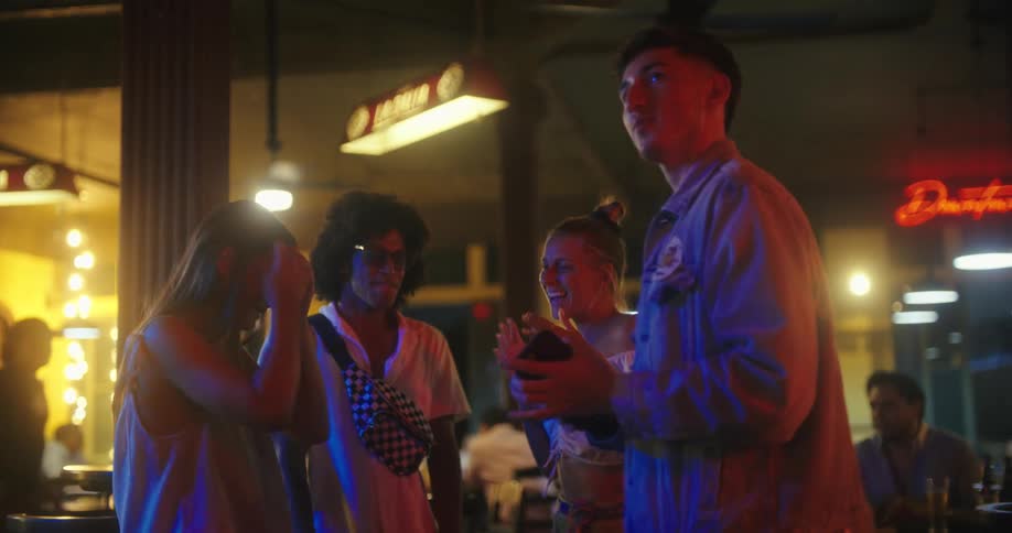 Friends at a club at night return to dancing after looking at a smartphone