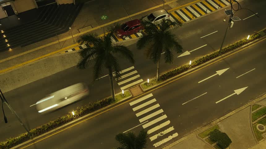 Cars travel along a city street under glowing lights at night