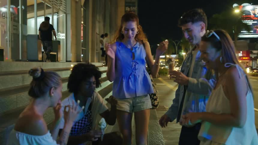 Friends laugh and hang out on a city street at night