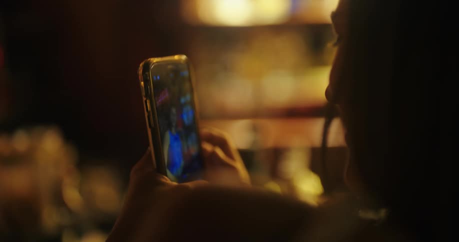 A woman smiles while watching a video on her phone