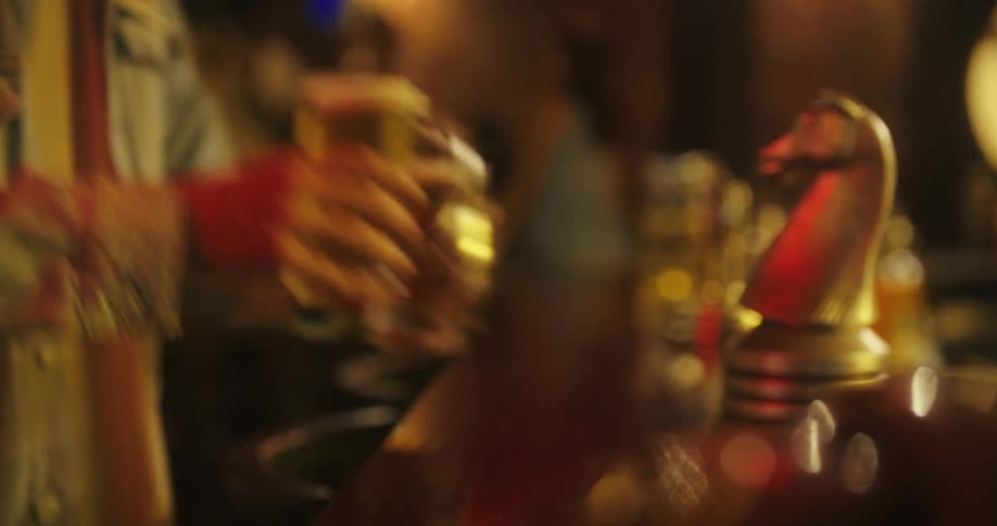 Bartender placing beer glasses on bar counter as customer walks over an picks them up