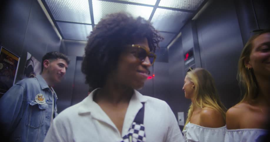 Woman grooms herself in the mirror while riding in an elevator with friends