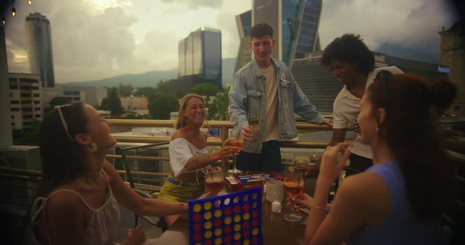 A group of friendstwo men and three womenon a rooftop at midday clinking glasses and enjoying a good time together