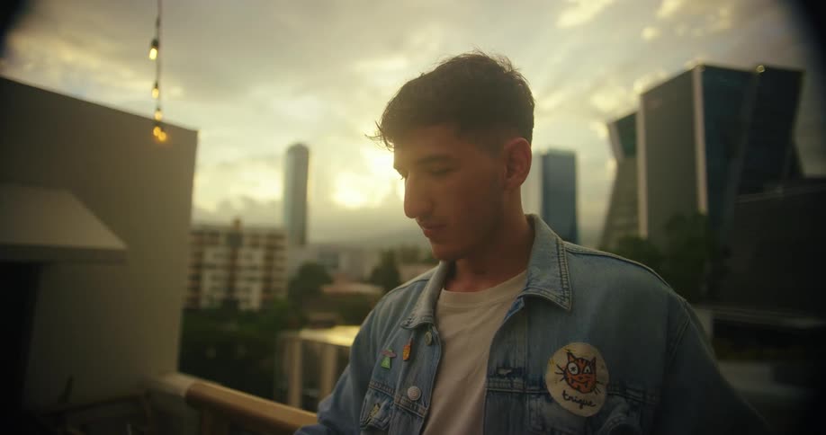 Man taking a selfie with a cellphone on an urban rooftop at sunset